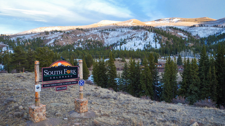 Sign for South Fork, Colorado, in front of a snowy mountain landscape