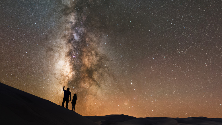 Silhouette of stargazers taking in the night sky and milky way over Great Sand Dunes National Park & Preserve