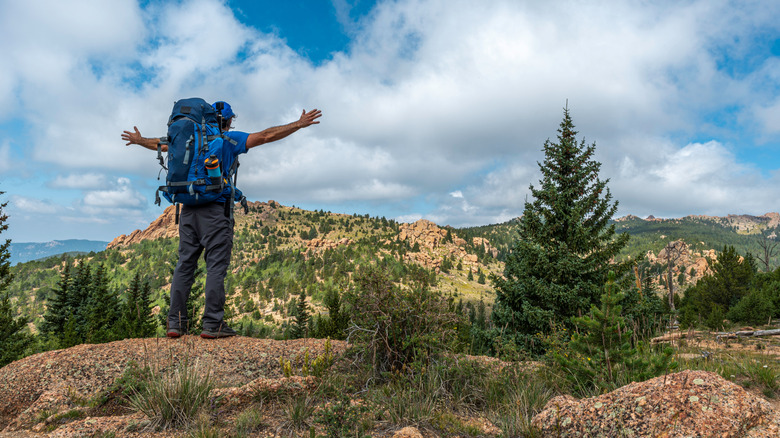 A backpacker at the top of a mountain in the Lost Creek Wilderness area