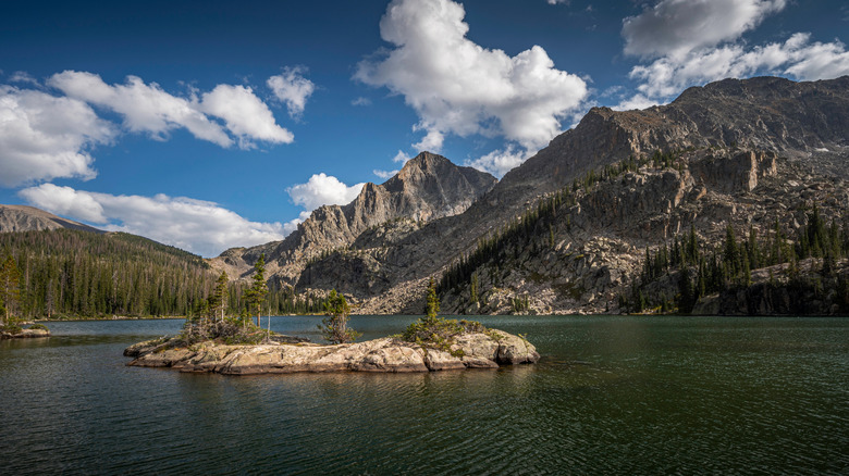 a small island visible in Lake Nanita, with mountains and trees surrounding the lake on the far side