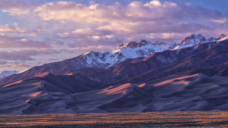 Golden hour light warms up the peaks of the Sangre de Cristo Mountains and the tops of the sand dunes in Great Sand Dune National Park, Colorado