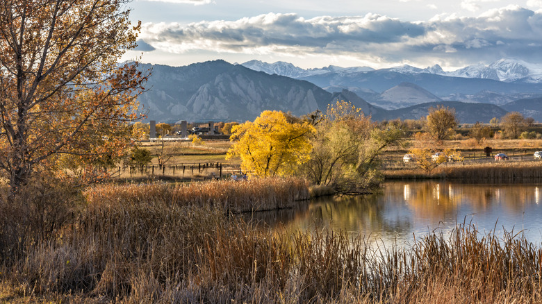A pond in Broomfield, Colorado, surrounded by fall foliage and snow-covered mountains