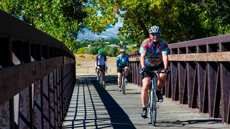 Three cyclists riding over a bridge over the South Platte River in Denver