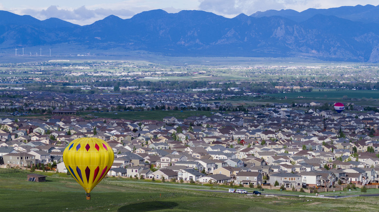 Hot air balloon rising over the Denver suburb of Erie, Colorado, with mountains in the background