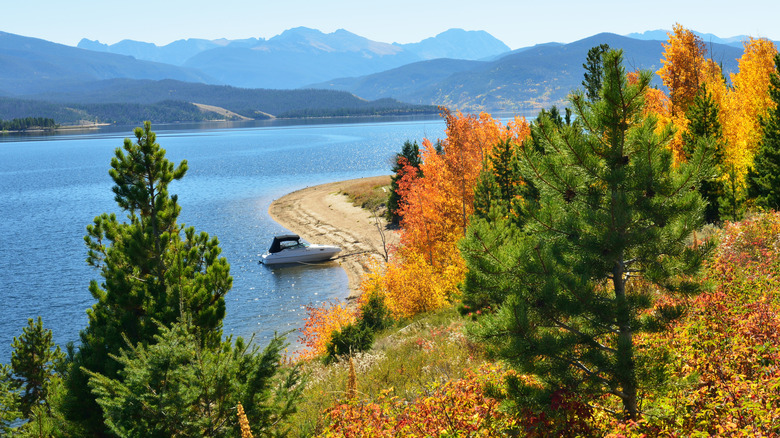 Autumn foliage on the shores of Lake Granby in Colorado with a boat resting near the beach