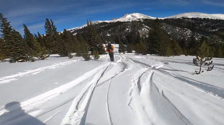 Skier's making their way down Geneva Basin Ski Area with snow-capped peaks in the distance