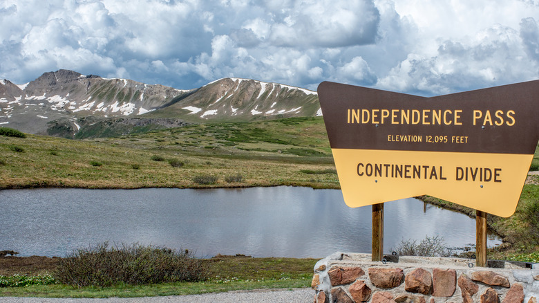 A sign for Colorado's Independence Pass with snow-capped mountains in the background