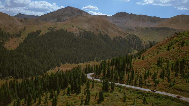 Cars driving along Independence Pass through forests and Colorado mountains