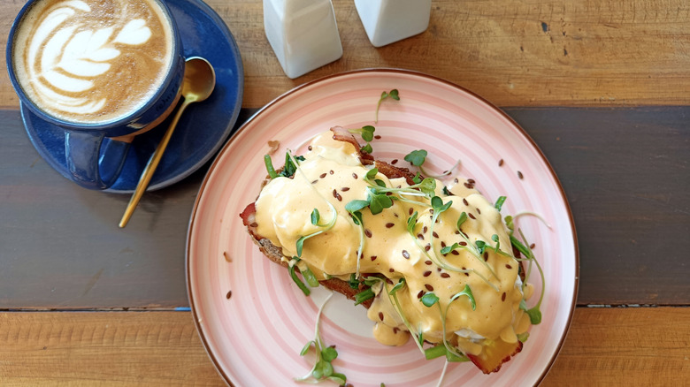 Plated eggs Benedict with a cup of coffee