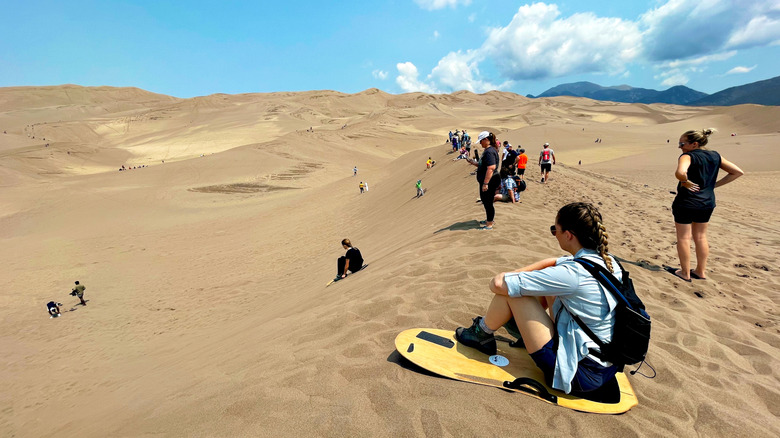 A group sand sledding in Great Sand Dunes National Park