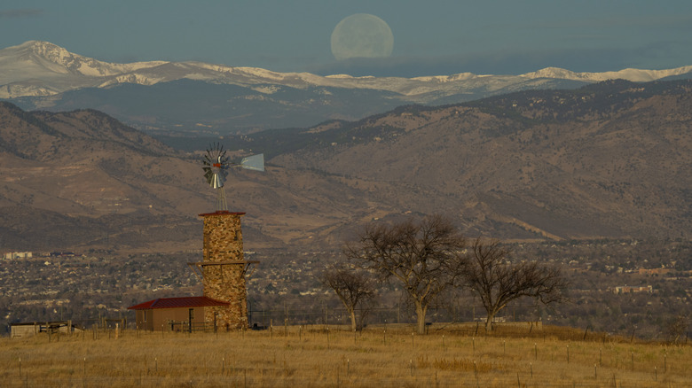 A windmill sits under snow-covered mountains near Castle Rock