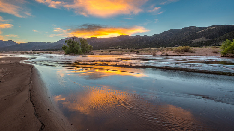 Sunrise over the mountains reflecting off the water in Medano Creek