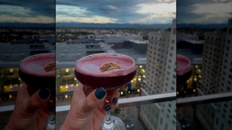 Woman holding a drink at 54thirty with the Rocky Mountains in the background