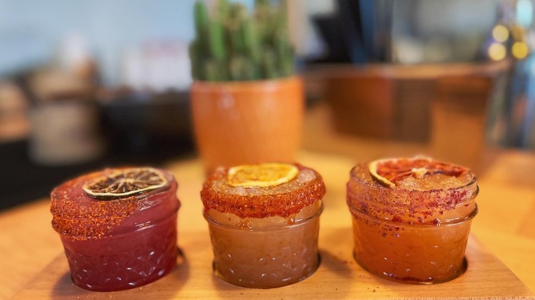 flight of three red and orange margaritas in small jars