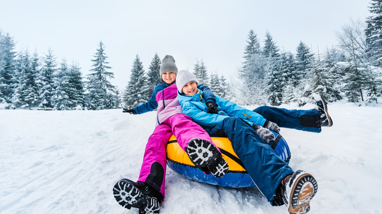 Two young children snow tubing