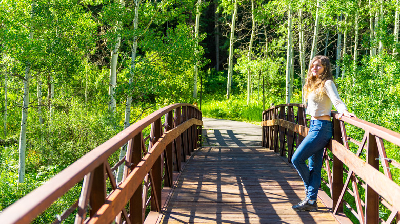 Girl posing on bridge in forest in Snowmass, Colorado