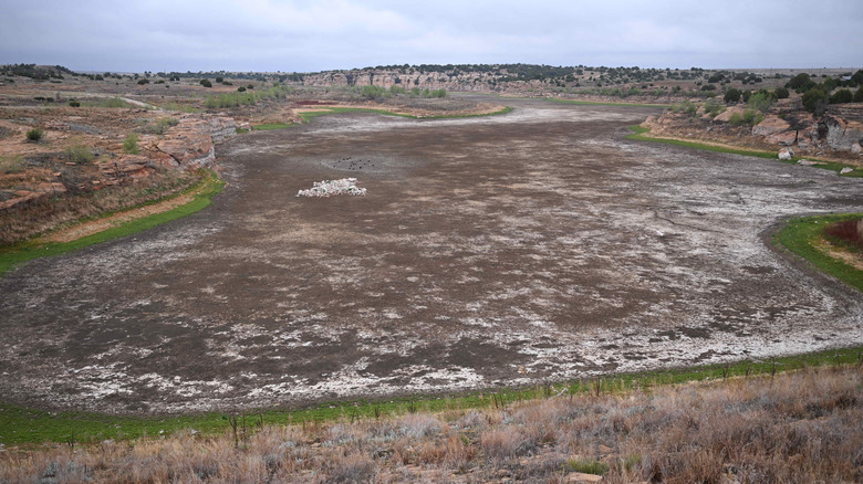 Dried out reservoir with birds and pile of fish against blue sky Two Buttes Reservoir Colorado