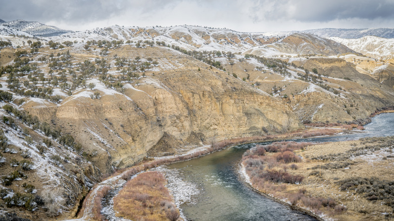Upper Colorado River lined by snow-covered mountains and sagebrush in Dotsero during winter.