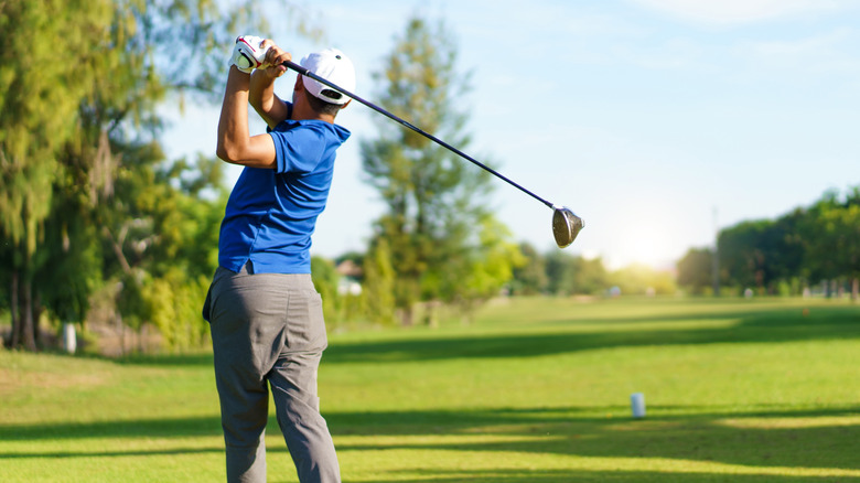 Man teeing off at a golf course on a sunny day