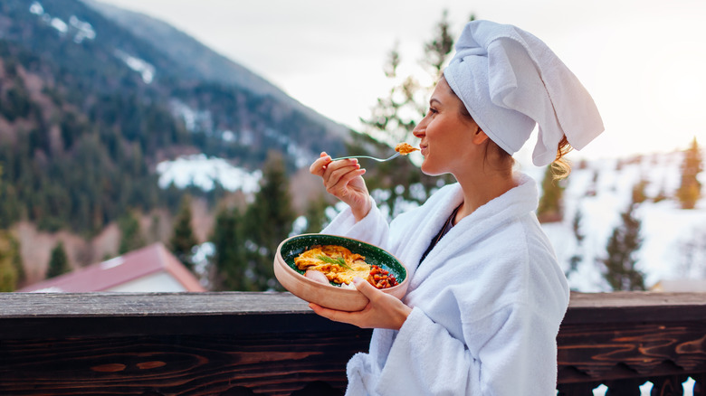 Woman in robe eating on balcony