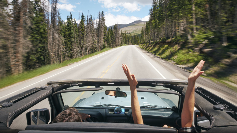 people in open top car on a Colorado road