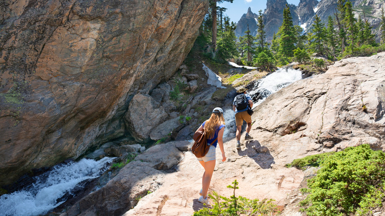 Two hikers near large boulder and creek
