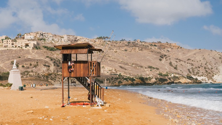 A lifeguard hut sits atop orange sands in Ramla Bay