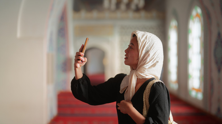 Female tourist covering up in Mosque and taking photo