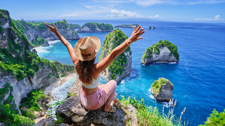 Girl sitting on rock above tropical coast in Southeast Asia