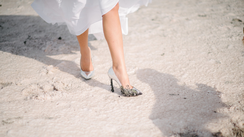 Shot of a woman's legs as she walks across a field of mud