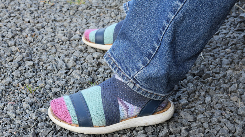 Person's feet on a rocky terrain with socks and sandals on