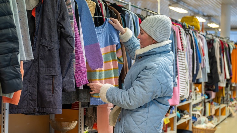 A woman picking out clothes at a thrift store
