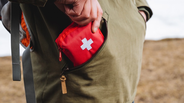 A person putting a first aid kit into their pocket