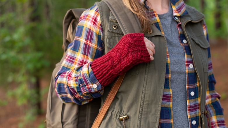 A hiker wearing fingerless gloves and layered clothing