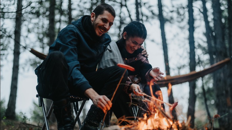 A couple cooking around a campfire