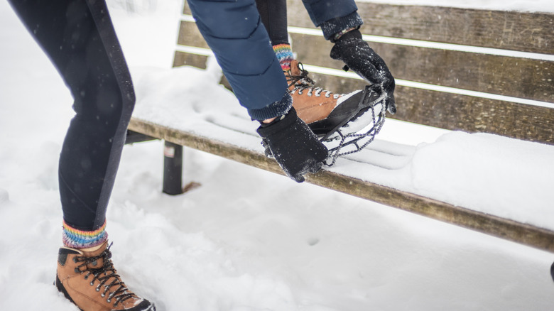 Woman putting on crampons in snow