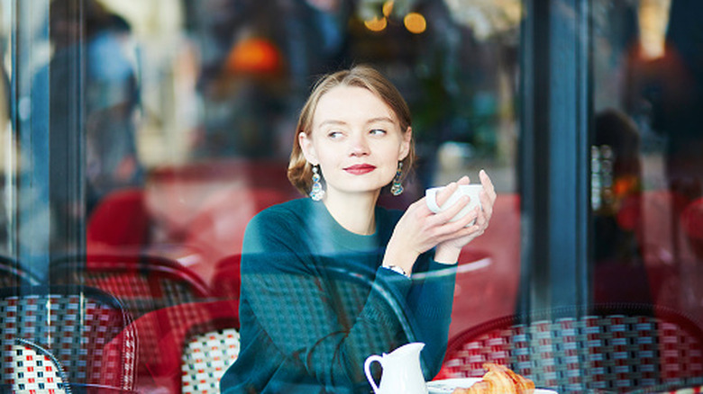 Young elegant woman drinking coffee in traditional cafe in Paris, France