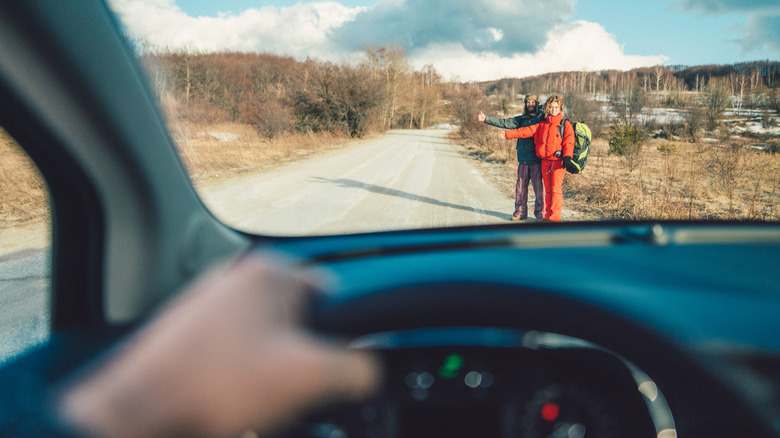 Young couple on the roadside waiting for car to stop