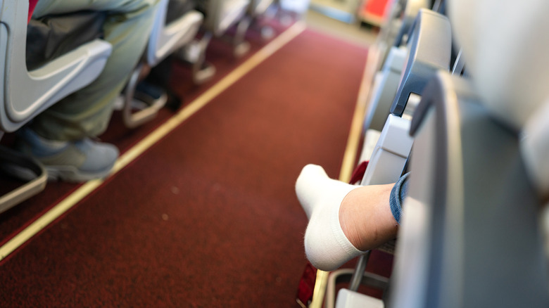A person sitting on a plane with no shoes on.