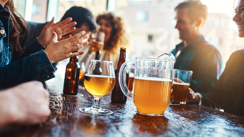Adults sitting at a bar with beer in front of them