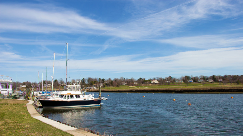 Small boats docked in Southport harbor next to grassy fields on a sunny day with blue skies