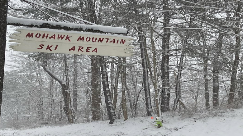 A snow-covered sign for the Mohawk Mountain Ski Area in a forest