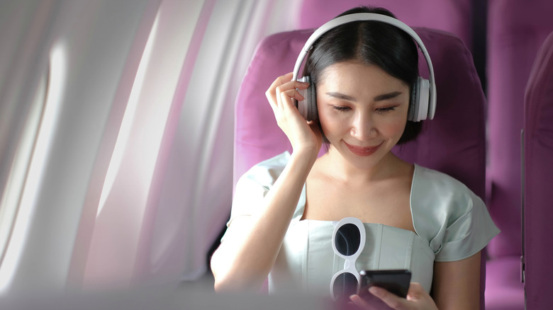A young woman wears noise-cancelling headphones on a flight
