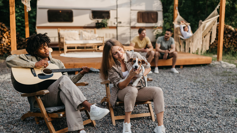 People sitting outside a parked RV