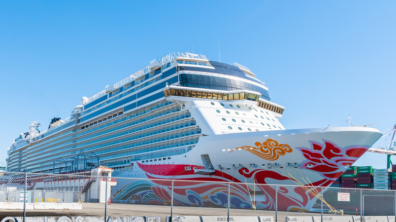 A big Norwegian Cruise Line ship looms in the foreground, settled into the harbor