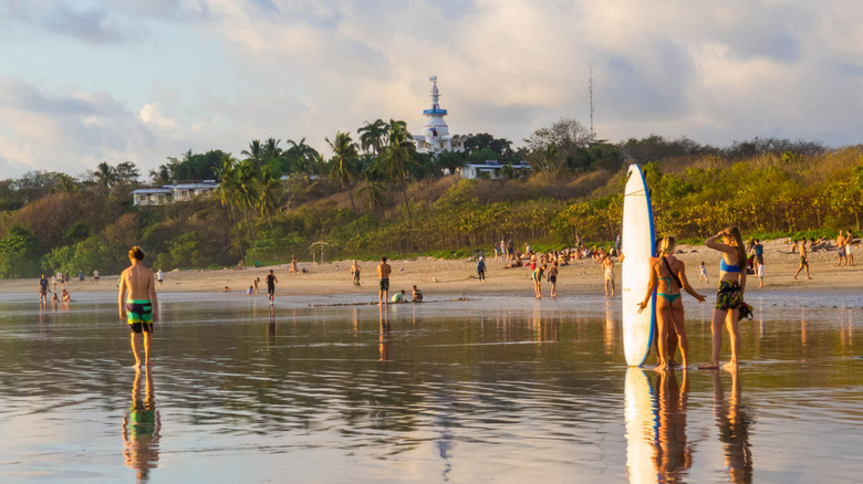 Surfers and swimmers gather on beach at Nosara