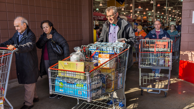 Shoppers leaving Costco stores with carts full of groceries