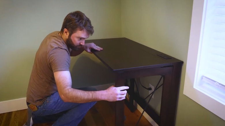 A man setting up the Stakmore folding desk in a room.