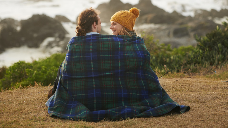 Couple sitting together wrapped in blanket on camping trip
