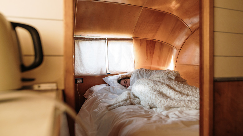 A person bundled up in a warm bed inside an RV